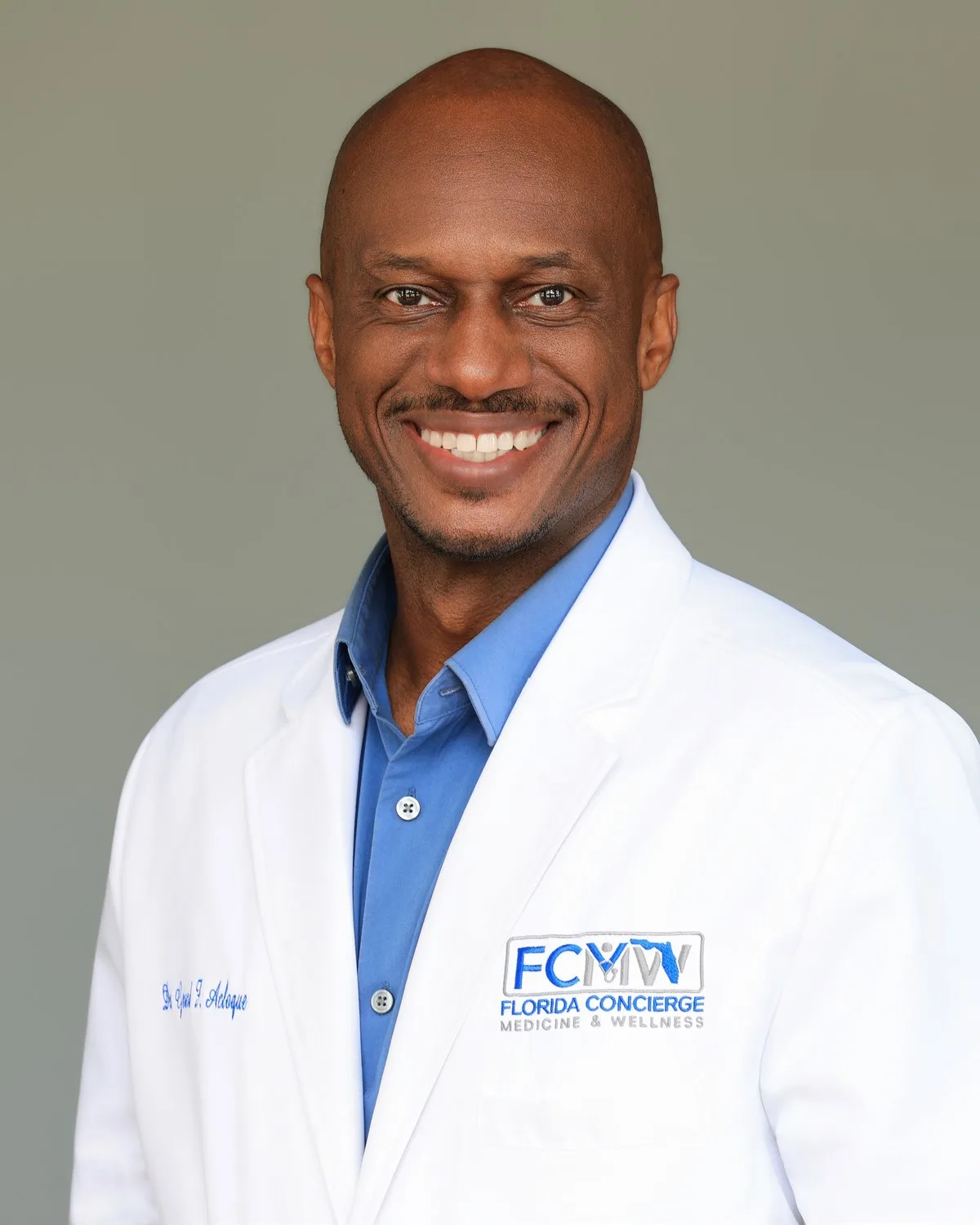 Dr. Gerard Acloque Jr., MD, smiling in his Florida Concierge Medicine & Wellness white coat